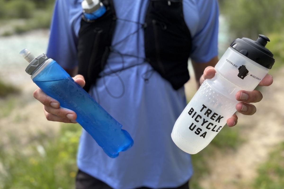 A runner holding a 500ml Salomon soft Flask and a bike bottle